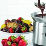 fuente de chocolate con un plato de frutas a un costado